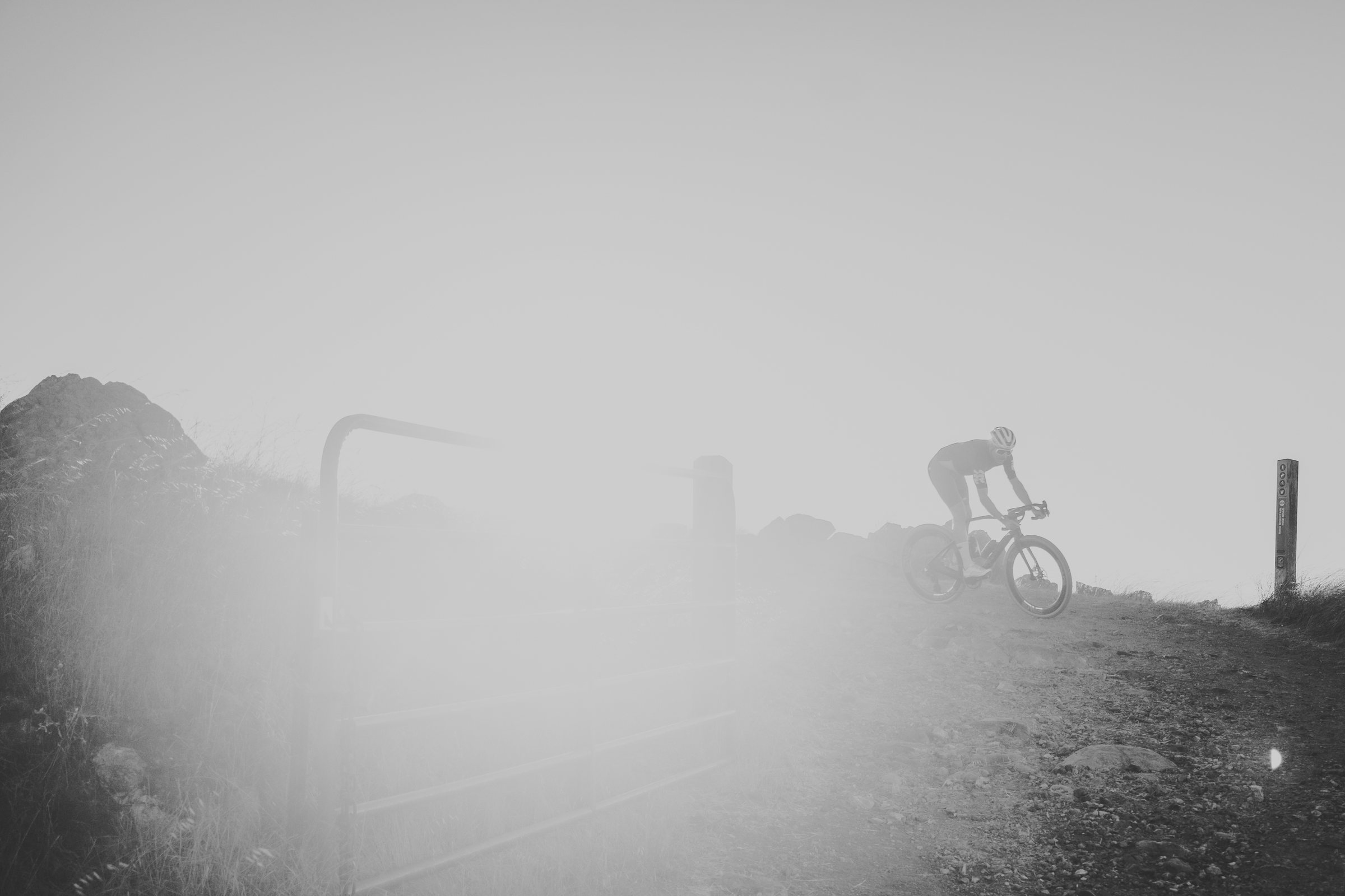 Distant rider climbing a foggy ridge, in black and white