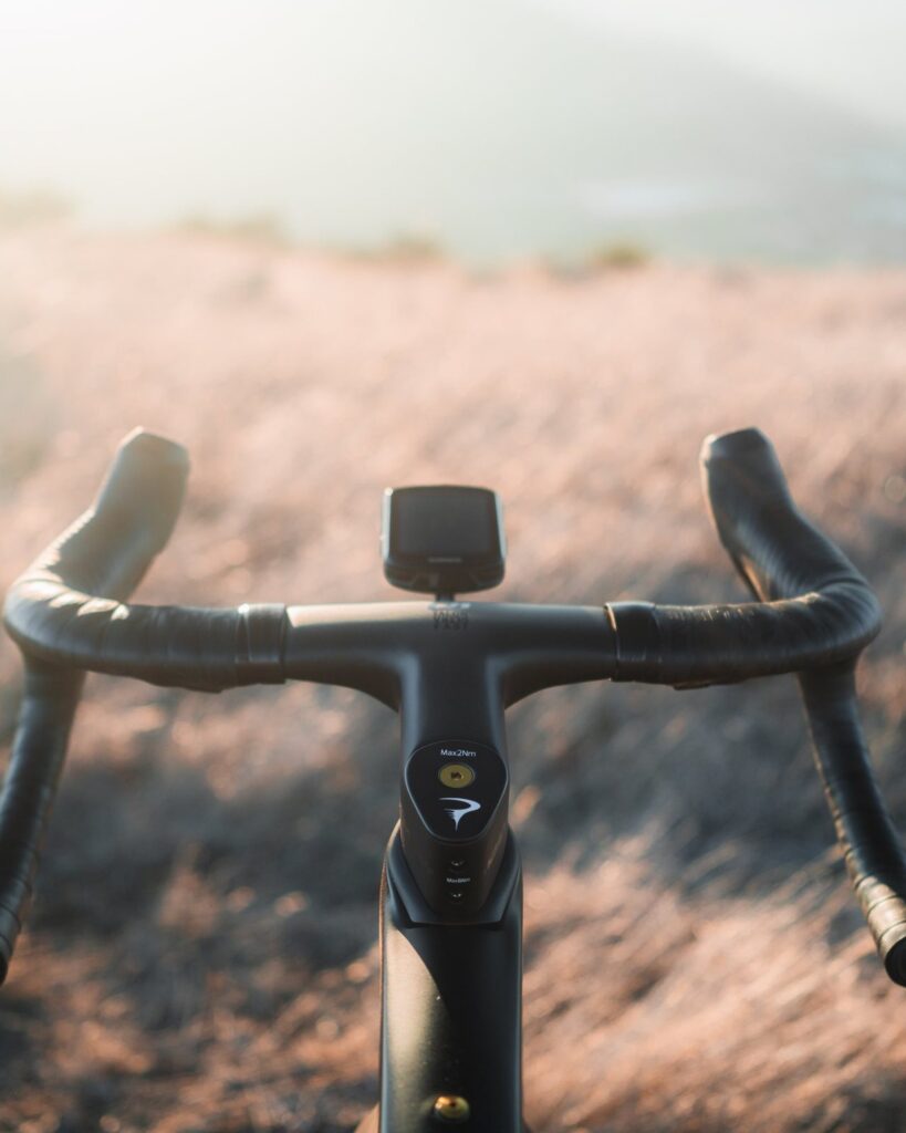 View along the handlebar of the Dogma GR with a head unit, over dry golden grass