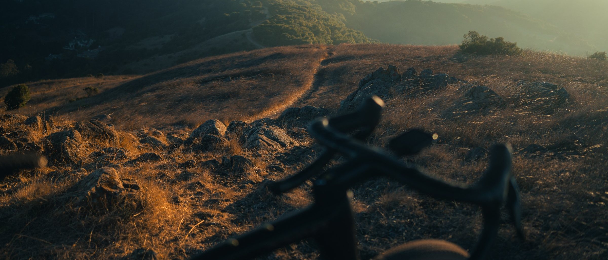 Handlebar in the foreground with ridgelines and low cloud behind