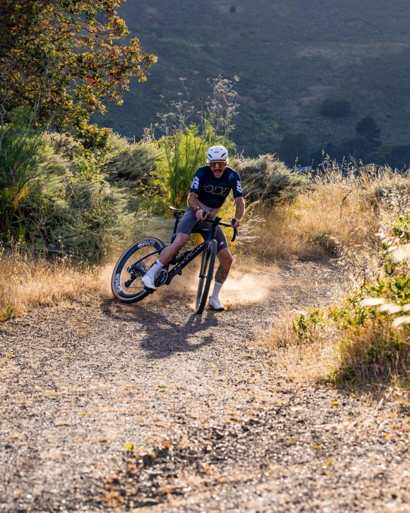 Rider sliding the rear wheel through a corner on a dirt trail