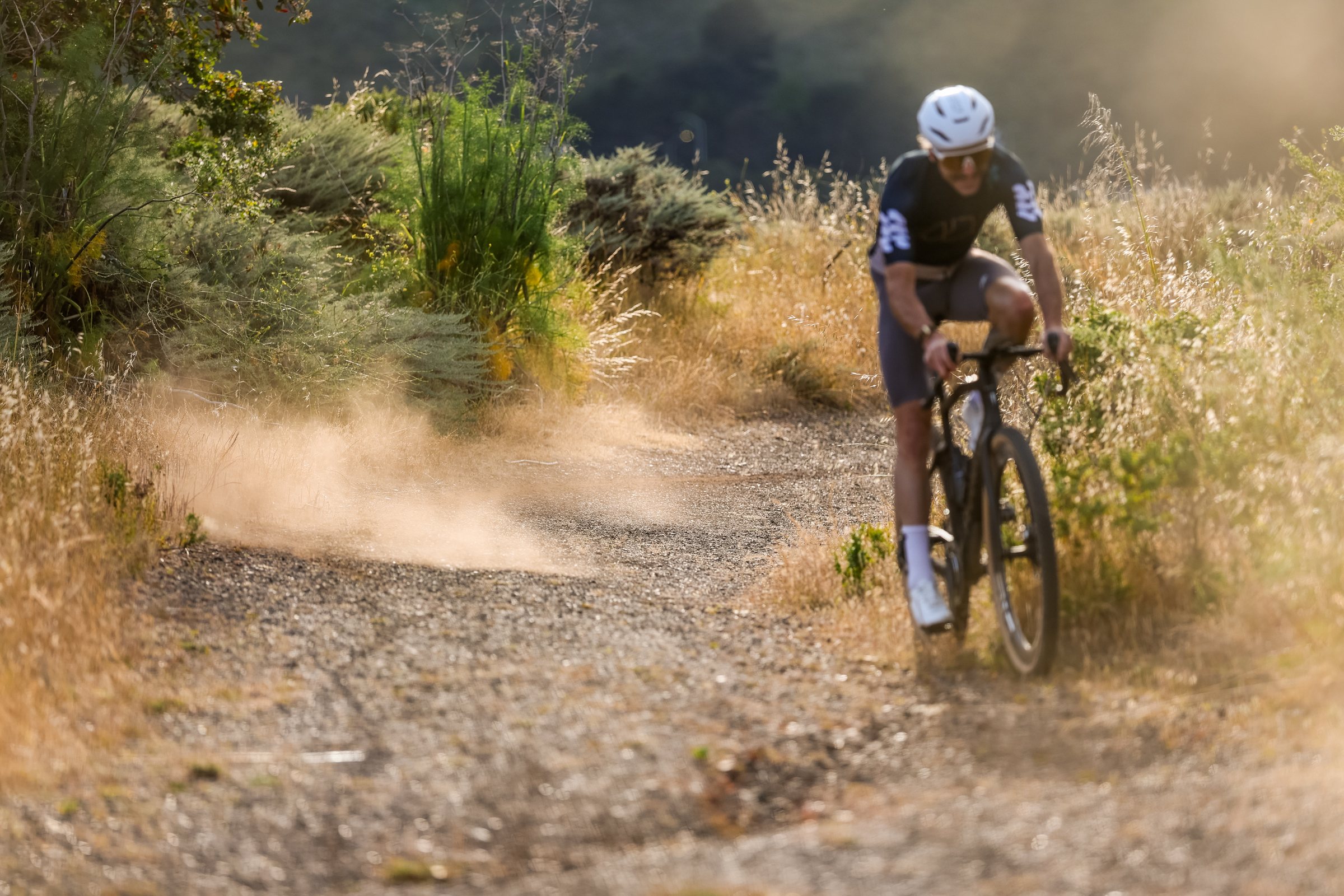 Rider kicking up dust through a corner on a dirt trail